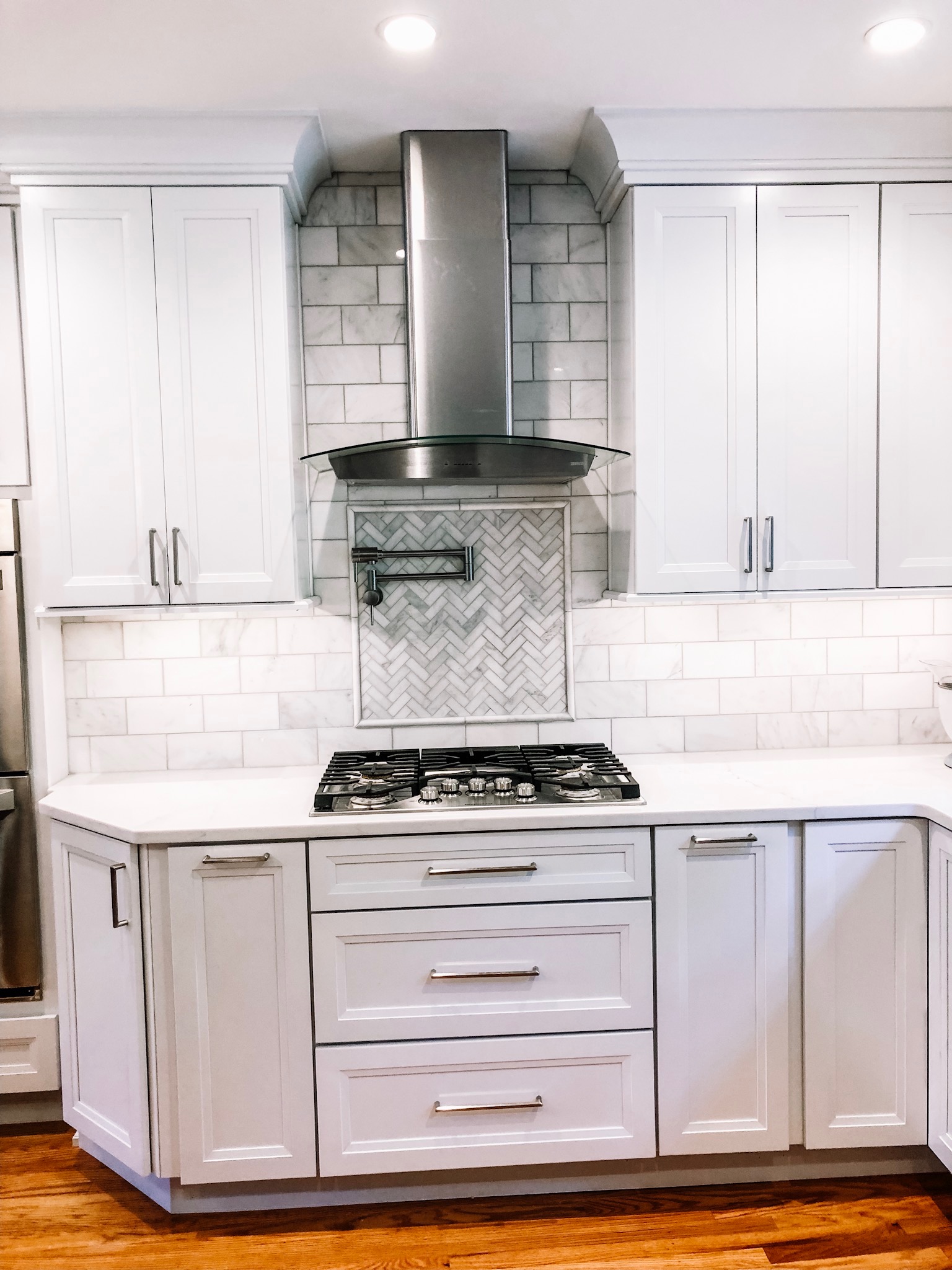 Marble Herringbone oven inset with Marble subway tile and white cabinetry.